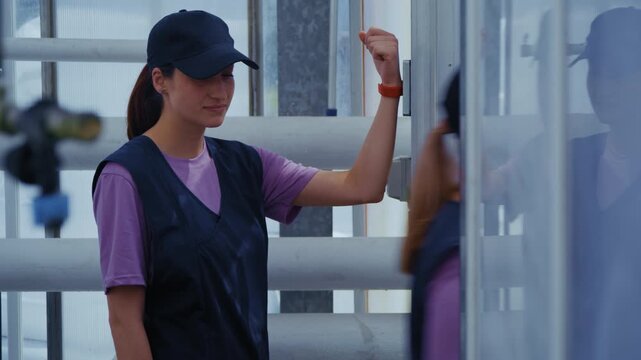 Industrial greenhouse workers pass through a secure checkpoint, using a key bracelet to unlock the gate.