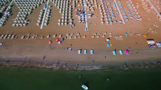 Aerial view of large equipped sandy beaches. Umbrellas and sun loungers for vacationers by the sea. Vacation on the Adriatic Sea. Ferris wheel. Traveling on Europe. Vacation in Italy Rimini 21.07.2025