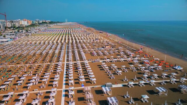 Aerial view of large equipped sandy beaches. Umbrellas and sun loungers for vacationers by the sea. Vacation on the Adriatic Sea. Ferris wheel. Traveling on Europe. Vacation in Italy Rimini 21.07.2025