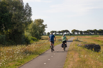 Fototapeta premium Cyclists take a bike ride along the Eem River in the rural area surrounding the centuries-old Coelhorst estate in Hoogland.