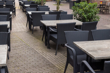 Empty black outdoor chairs and tables in front of a restaurant