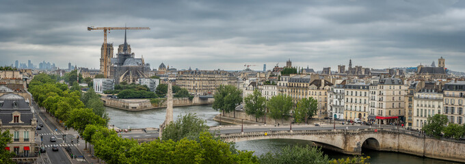 Fototapeta premium Paris, France - 07 19 2025: Notre Dame de Paris. Panoramic view of Notre-Dame cathedral, The Seine and La Defense district from the top of Arab World Institute
