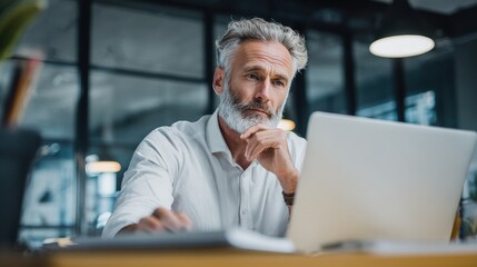 Mature business man executive manager looking at laptop computer watching online webinar training or having virtual meeting video conference taking notes, doing market research working in office., no