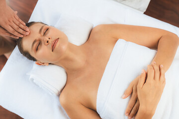Panorama top view of woman enjoying relaxing anti-stress head massage and pampering facial beauty skin recreation leisure in dayspa modern light ambient at luxury resort or hotel spa salon. Quiescent
