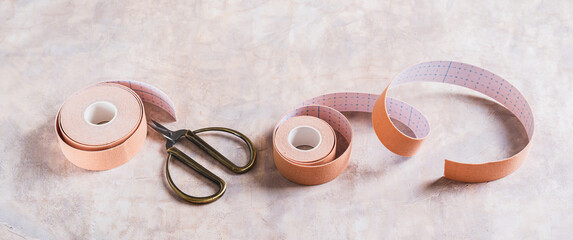Neutral colored kinesio tapes for face lifting and scissors on the table web banneer