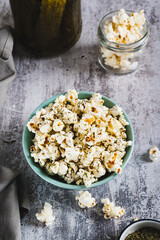 Delicious popcorn with dill and pickles in a bowl on the table vertical view