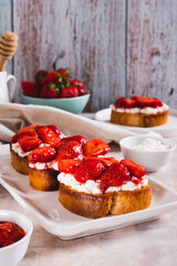 Appetizing bruschetta with ricotta and stewed strawberries on a plate vertical view