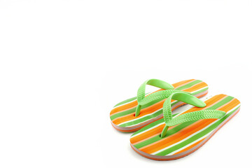 Tongs ray&eacute;es orange, vert et blanc pos&eacute;es sur fond blanc avec espace n&eacute;gatif copyspace, accessoire iconique et color&eacute; symbolisant l&rsquo;&eacute;t&eacute; et les vacances