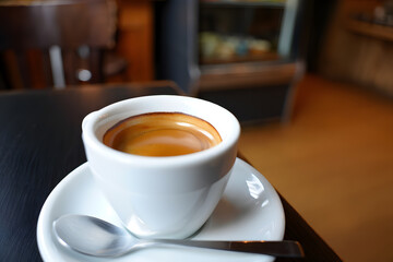 Fototapeta premium Espresso Coffee in White Cup, Warm Lighting, Cafe Setting, Close-Up Shot