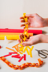Handmade paper chain on women's palms and items for its production vertical view