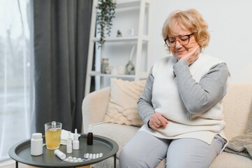 portrait of sick senior woman posing at home with sore throat