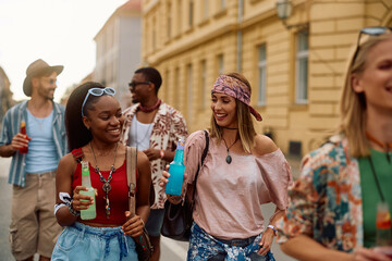 Happy female friends enjoying in cold drinks while going to open air music festival in summer.