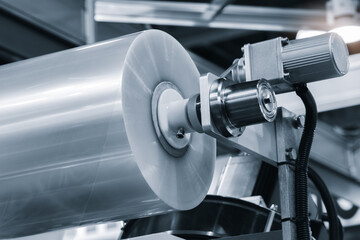 A machine with a roll of polyethylene plastic wrapping film on it. The machine is in a factory....