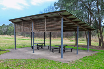 Photograph of a large outdoor undercover picnic shelter amongst trees in public parkland in...