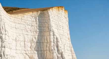 Majestic white chalk cliffs rise against a clear blue sky
