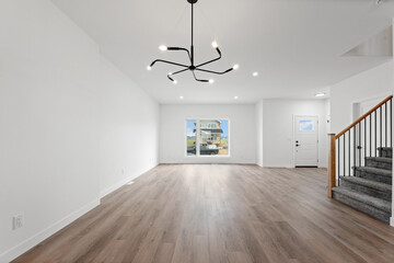Large, empty living room with a black chandelier hanging from the ceiling