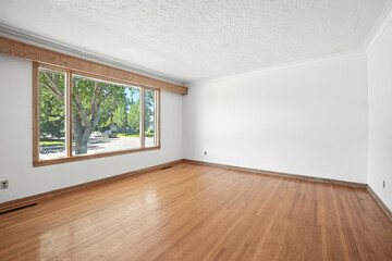 Large, empty room with a window and a wooden floor