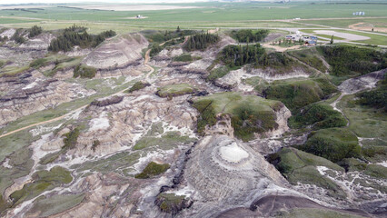 Drumheller Alberta Canada Aerial View of Rugged Badlands Terrain With Eroded Hills in Horseshoe Canyon and Vegetation distinct stratified layers and scattered patches of vegetation under cloudy skies
