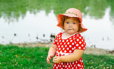 Little Girl in a Polka Dot Dress Enjoys Nature by the Water During a Sunny Day