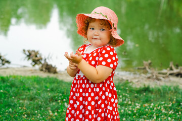 Little Girl in a Polka Dot Dress Enjoys Nature by the Water During a Sunny Day