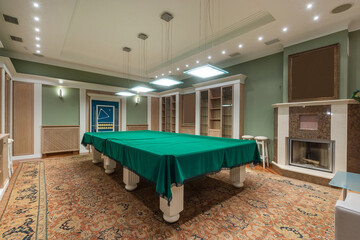 A spacious recreation room features a green billiards table under contemporary lighting. Tasteful furnishings and decor create a comfortable atmosphere for leisure activities.