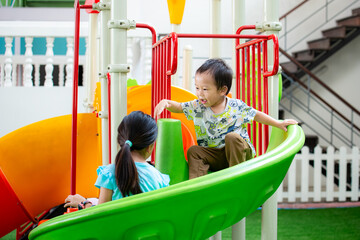 Children having fun playing together at the playground on a sunny day. Sister and brother are...
