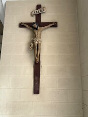 Wooden crucifix featuring the inri inscription hanging on a white brick wall, representing jesus...