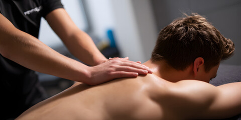 Physiotherapist providing a massage to the back of a young athlete in a sports rehabilitation clinic, showcasing effective techniques for recovery in this high quality photo.