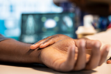 African american medic uses her smartwatch to measure pulse of a male patient, modern digital gadgets at the routine checkup. Heartbeat measurement with a fitness tracker accessory. Close up.