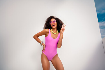 Trendy young woman in pink swimwear posing outdoors in stylish fashion, enjoying summer vibes with cheerful expression