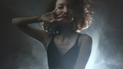 Contemporary dance artistry: female performer in fashionable outfit dancing through atmospheric haze