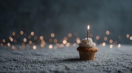 Single cupcake with candle on a textured surface.
