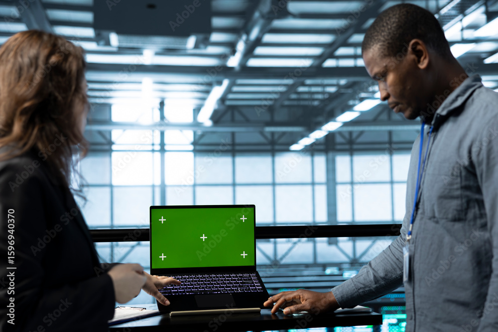 Poster admins using green screen laptop in data center, managing server virtualization. it professionals us