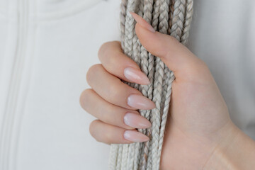 Manicured hand holding white textured braids, elegant beauty and hair close-up.