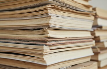 Large stack of old paper documents, books, neatly organized. Close-up on numerous paper files piled high, suggesting archive, library, office storage. Records represent volumes of literature,