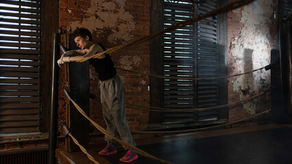 A woman in a boxing gym, portrait by the ropes, cinematic style, dark tones. Training and overcoming oneself, motivation