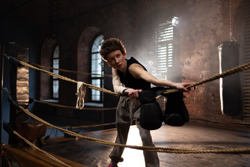 Boxer woman with short hair pausing on ropes, cinematic gym training atmosphere