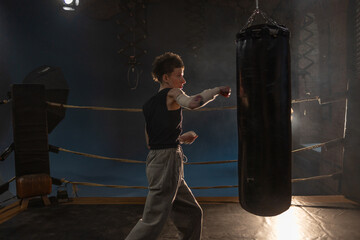 Boxing with a punching bag, sports achievements concept, female wrestler in a boxing ring, cinematic image, mood, motivating stories