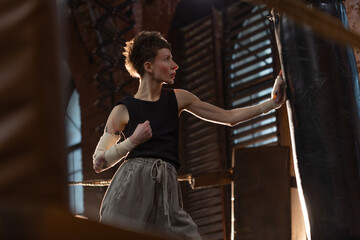 Short-haired boxer pausing workout, leaning on ring ropes with cinematic intensity