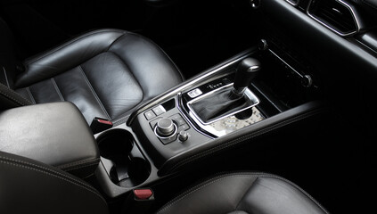 The strict design of the car interior in dark tones, trimmed with leather of different textures and...