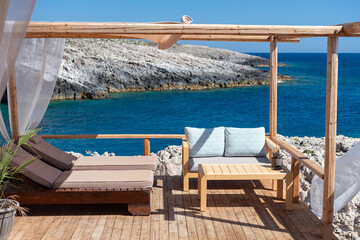 A luxurious and tranquil lounge area with comfortable sunbeds on a wooden deck overlooking the deep...