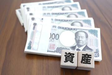 札束と資産の文字ブロック・金融資産や投資のイメージ