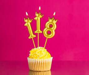 Yellow birthday cupcake with a number 118 candle - Birthday card on a pink background
