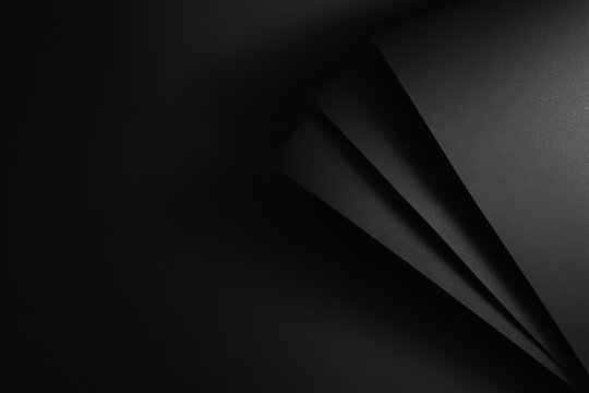 Abstract geometric composition of black layered paper creating a pattern of shadows and lines that gives a sense of depth and texture