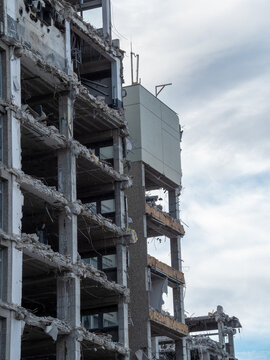 Building demolition process reveals structural details in urban setting during overcast weather