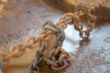 Rustic steel chain with hook is using to fastening and restraining on the heavy object, secure for the transportation. Transporation industrial equipment object, close-up with selective focus.