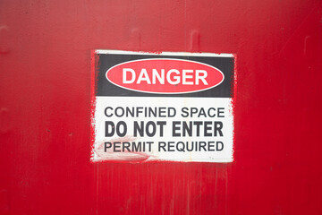 Danger warning sign of "Confined Space" work place, risk for asphyxiation fatality. Industrial equipment safety sign, close-up.