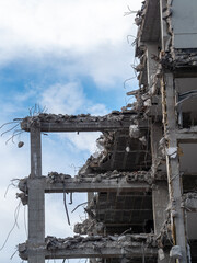 Demolition of a high-rise building leaves exposed concrete structure against blue sky
