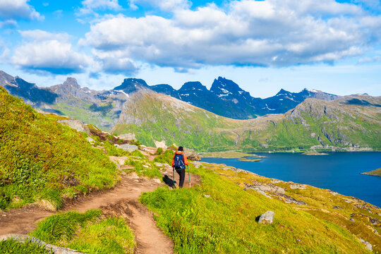 Female hiker walking on trekking path from Ryten to Kvalvika beach, Lofoten Islands, Norway