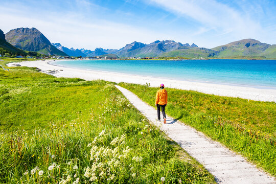 Female tourist walking on path to Ramberg beach in summer, Lofoten Islands, Norway